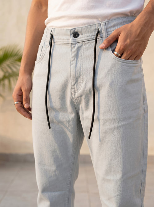 Snipes Carrot Fit denim jeans, slim fit style, with classic five-pocket design and light wash, displayed on a hanger.